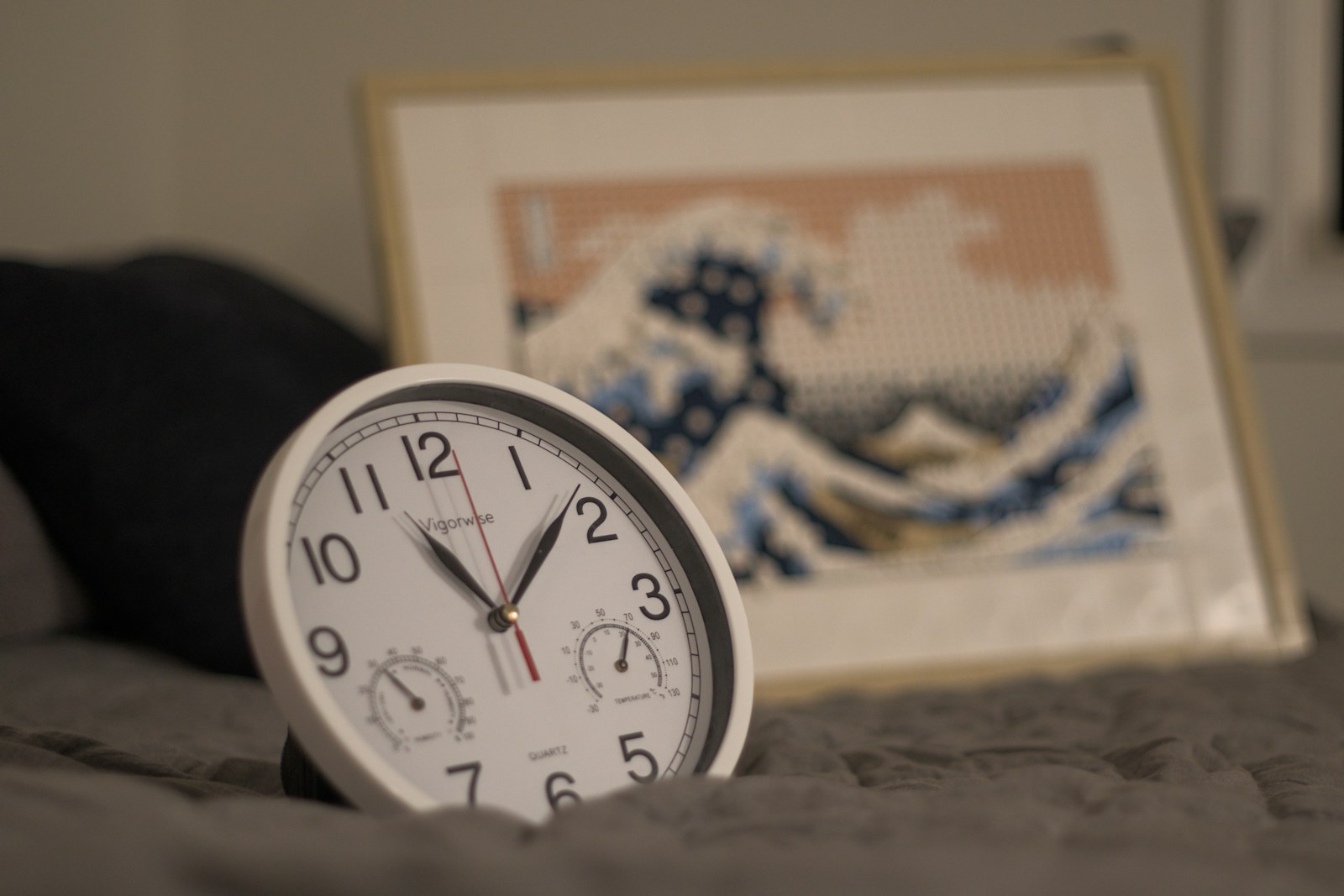A white clock sitting on top of a bed